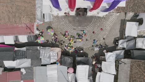 Static-top-down-aerial-footage-of-the-Iglesia-de-Santa-Tomás-with-vendors-on-the-steps-and-people-walking-through-the-market-in-Chichicastenango,-Guatemala