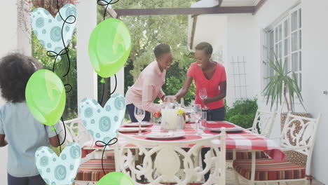 animation of balloons over happy african american family preparing dinner in garden