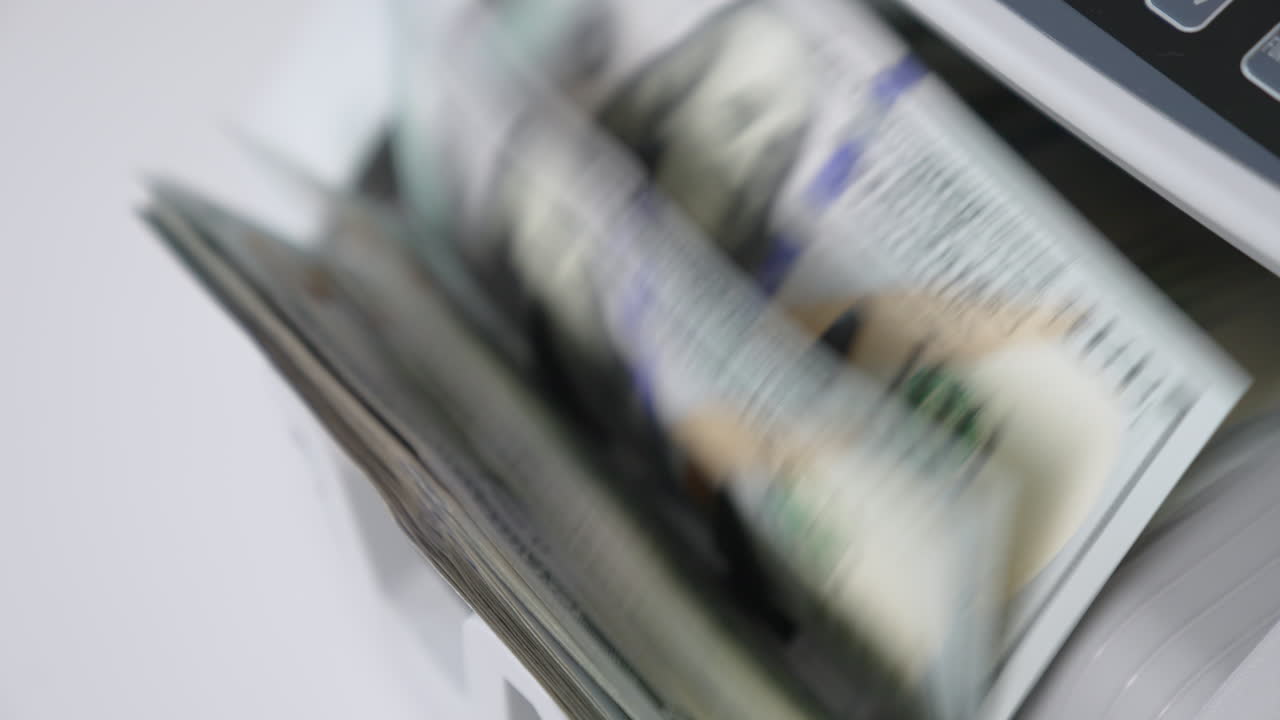 Rotating mechanism turning quickly hundred dollar US bills. Work of cash counting machine close up. Blurred background.