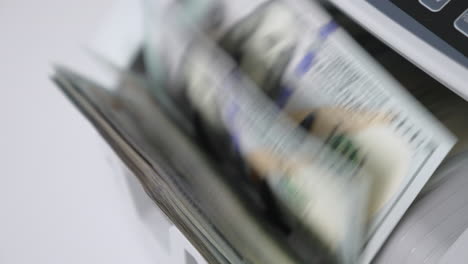 rotating mechanism turning quickly hundred dollar us bills. work of cash counting machine close up. blurred background.