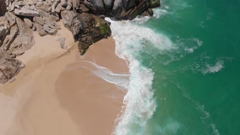 vista de pájaro de las olas que chocan contra la orilla junto a las rocas