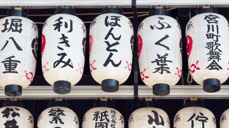 File di lanterne di carta bianche con calligrafia nera pendono in un santuario tradizionale di Kyoto.