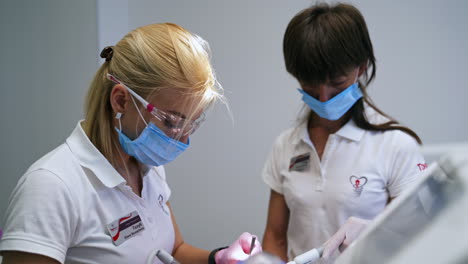 dentist uses drill machine device and metal tool in the teeth treatment of patient. dental help in modern clinics.
