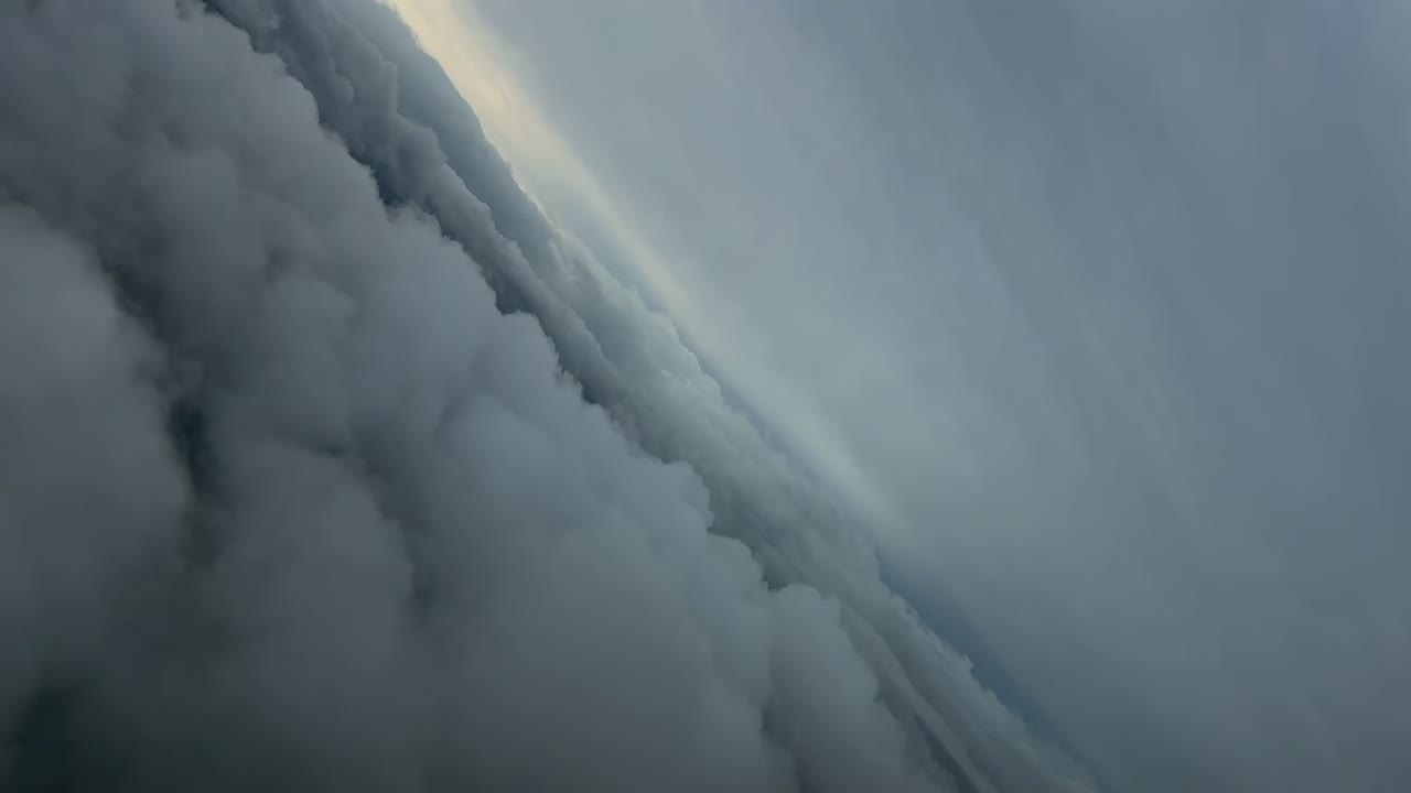 An immersive jet cockpit view while flying at supersonic speed doing a left step turn between layers of menacing grey clouds