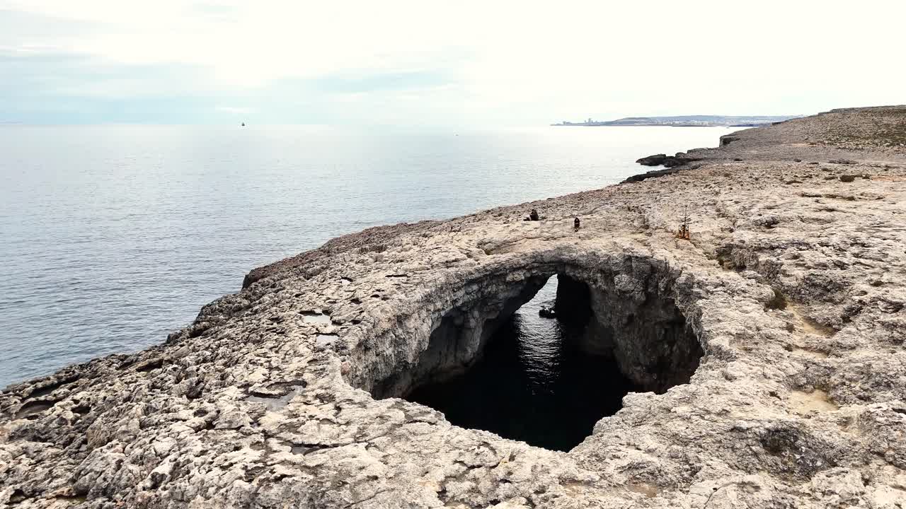 La Laguna Corallina Il-Qarraba a Mellieħa, Malta, mostra una dolina di crollo ellittica formatasi da una grotta marina costiera all'interno dell'altopiano di Calcare Corallino Superiore, collegata al Mediterraneo tramite un tunnel vicino alla baia di Armier.