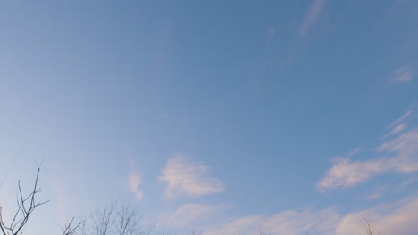 tilt-down-shot-of-blue-cloud-spotted-sky-at-sunset-with-an-abandoned-brick-building-on-the-horizon