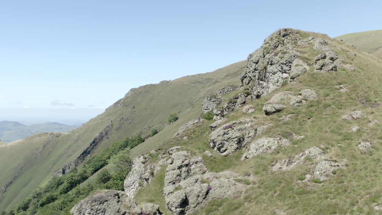 Aerial view flying towards rocky outcrop on green mountainside, Pyrenees, Col de Sourzay, Lecumberry, France