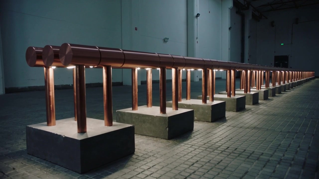 Starting pan, camera revealing copper pipe and posts on bases in large hall, showing rhythm