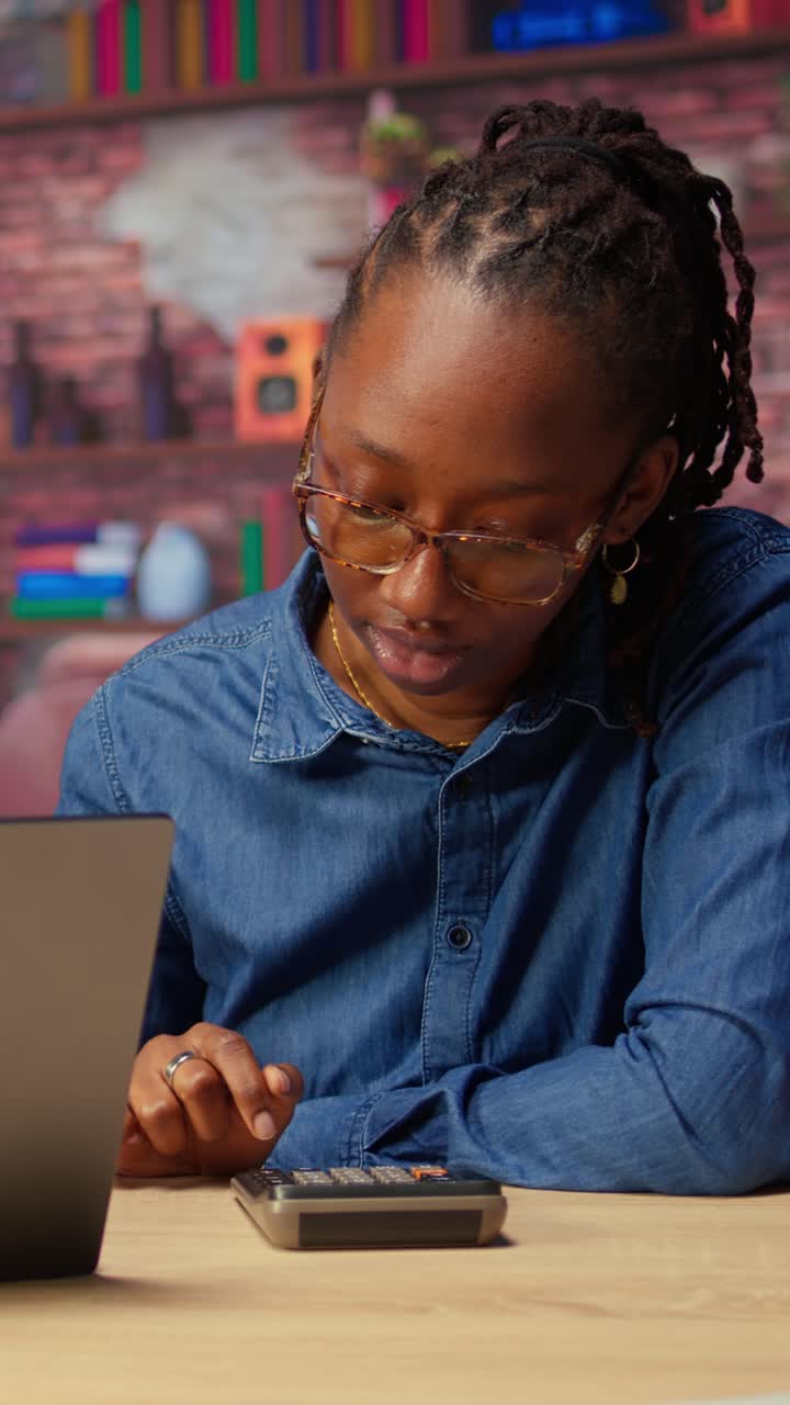 African American Woman Working on Laptop and Calculator at Home