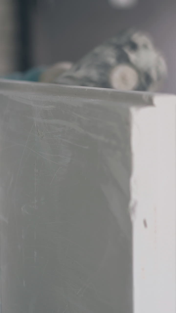 professional man holds special wall measures and beats gypsum plasterboard construction with rubber hammer closeup