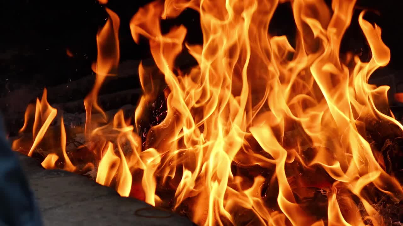 Detailed view of vibrant flames consuming wooden logs, showcasing intense heat and dynamic movement.