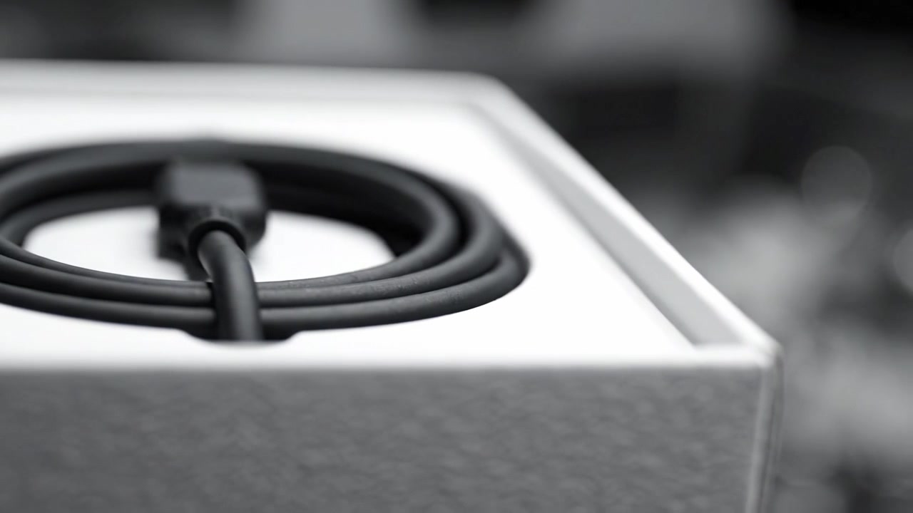 Detailed Close-Up of a Black Charging Cable Coiled Inside a Minimalist White Box with Soft Focus Background Highlighting Its Sleek Design and Texture