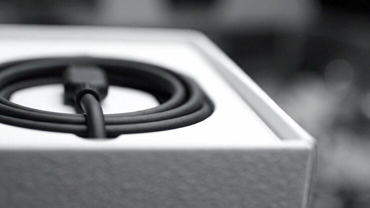 Detailed Close-Up of a Black Charging Cable Coiled Inside a Minimalist White Box with Soft Focus Background Highlighting Its Sleek Design and Texture