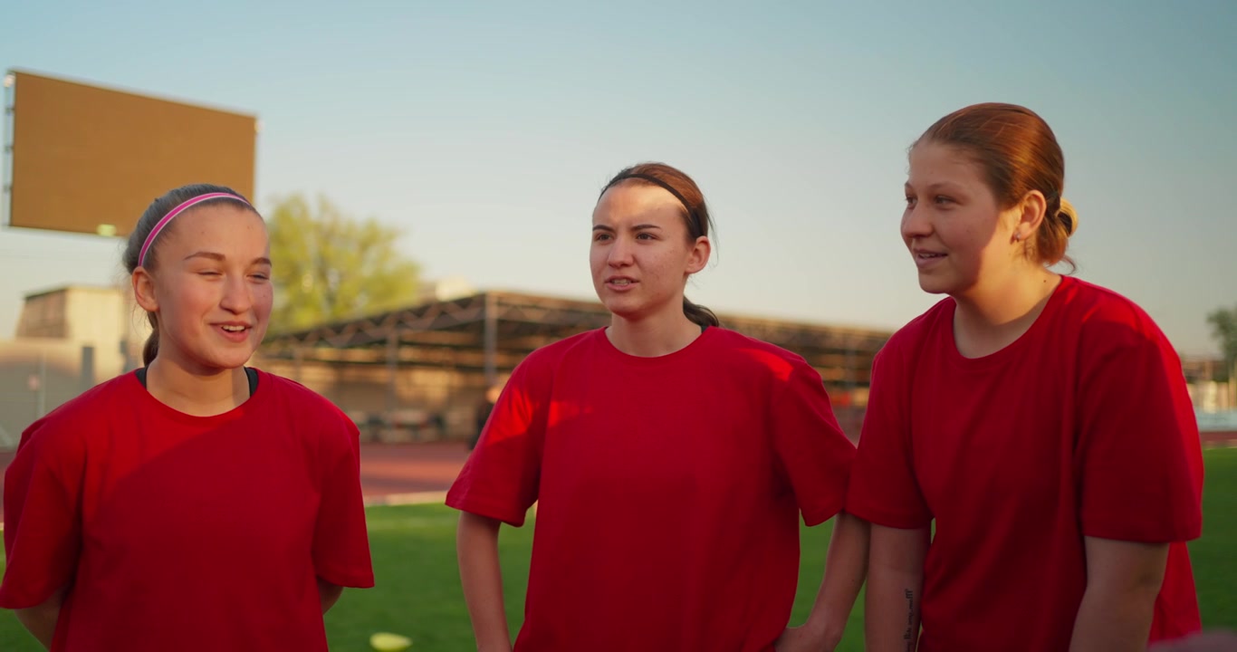 Unga kvinnliga atleter i röda t-shirts på en idrottsplan