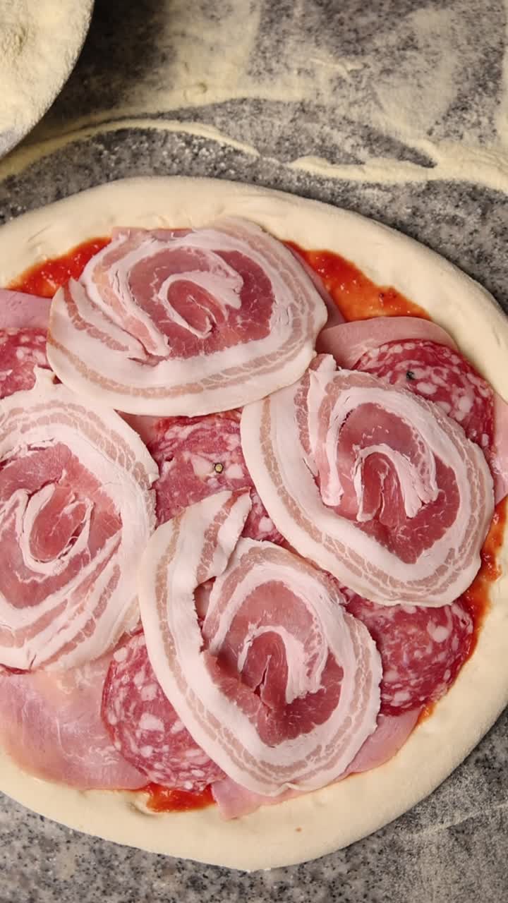 Pizza cruda guarnita con salame, prosciutto e pancetta