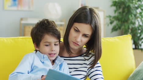 Junge-Mutter-Sitzt-Und-Umarmt-Ihren-Kleinen-Sohn-Auf-Der-Couch-Im-Wohnzimmer