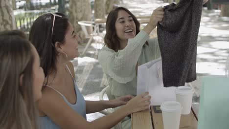 latin woman showing shirt to pretty friends on a terrace