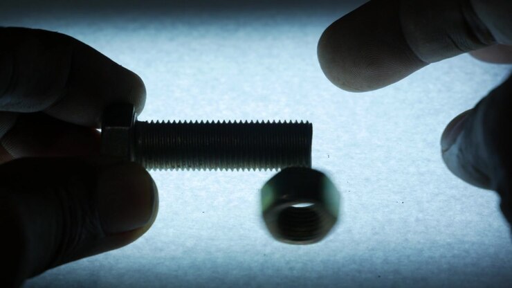 Hands Removing Metal Hex Nut from Threaded Bolt