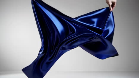 hands holding and draping flowing blue fabric