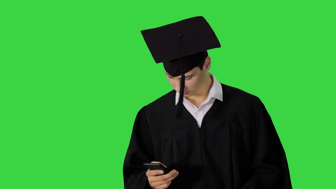 Graduate student walking hand texting message on the phone on a Green Screen, Chroma Key
