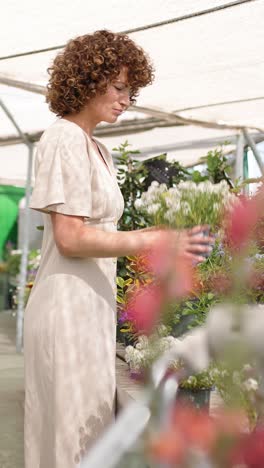 woman curating floral arrangement in a sunny greenhouse. vertical