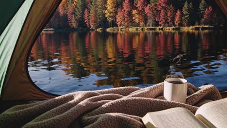 cozy camping scene from inside a tent, overlooking a lake with autumn trees