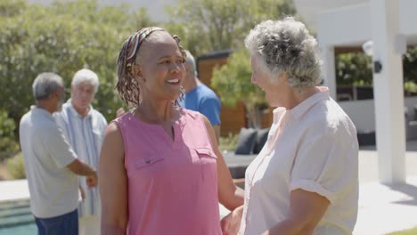 felices amigas mayores diversas abrazándose en una fiesta de jardín soleada, sin alteraciones, en cámara lenta