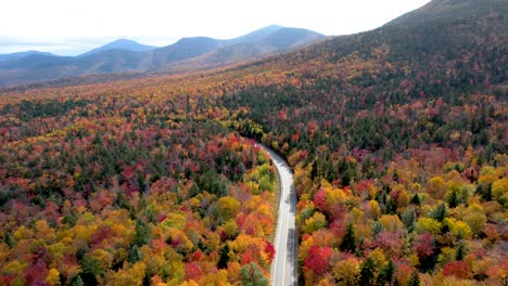 aerial view of road through mountains with autumn changing leaves