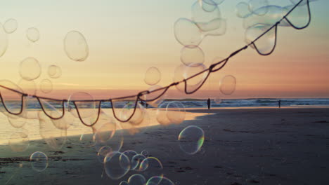 giant bubble wand floats bubbles over vibrant beach sunset