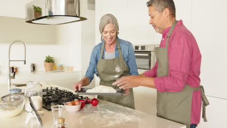 baking bread, multiracial senior couple enjoying time together in modern kitchen, at home