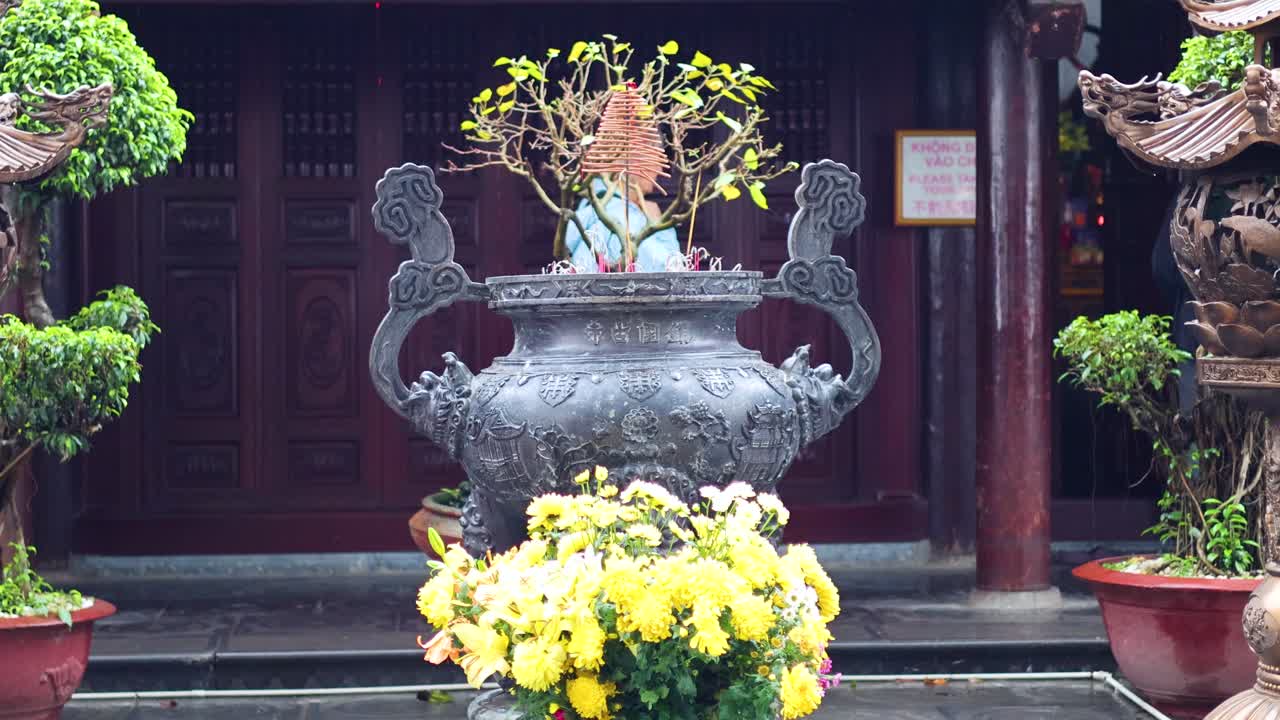 gente caminando más allá del quemador de incienso en el templo