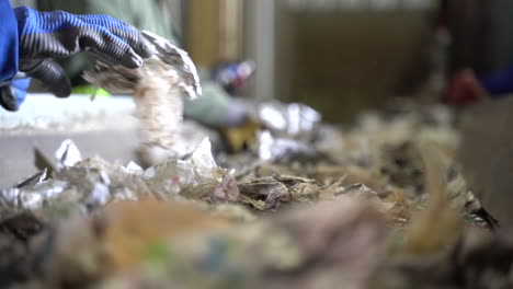 cinematic shot of shredded milk cartons being sorted on conveyor belt by hand