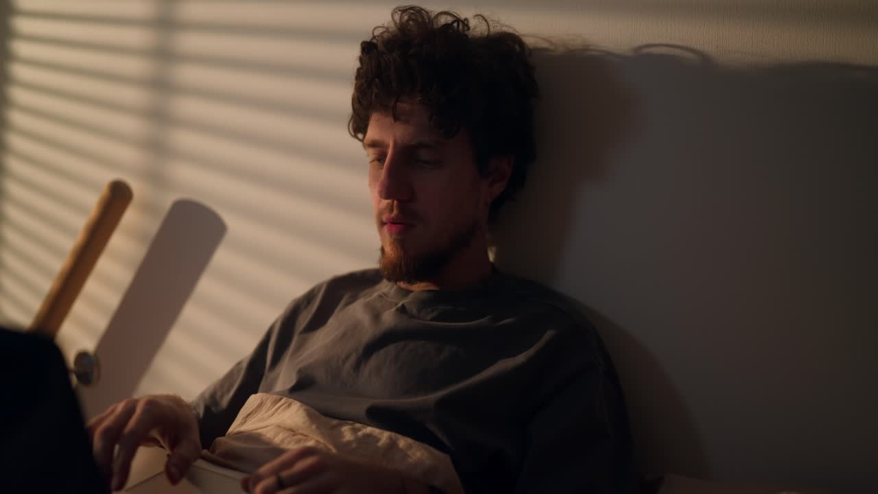 밤에 침대에서 노트북으로 일하는 남자