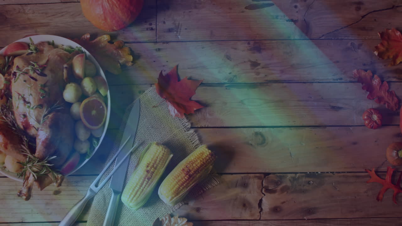 Thanksgiving table set with turkey, corn, and autumn leaves on wooden surface