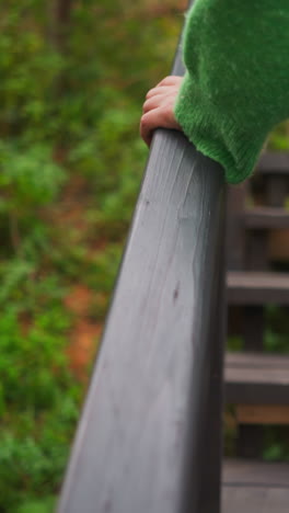 mujer sosteniendo la barandilla de la escalera. subiendo escalones de madera a la casa de campo para alquilar a los turistas. movimiento activo y caminar en medio del bosque