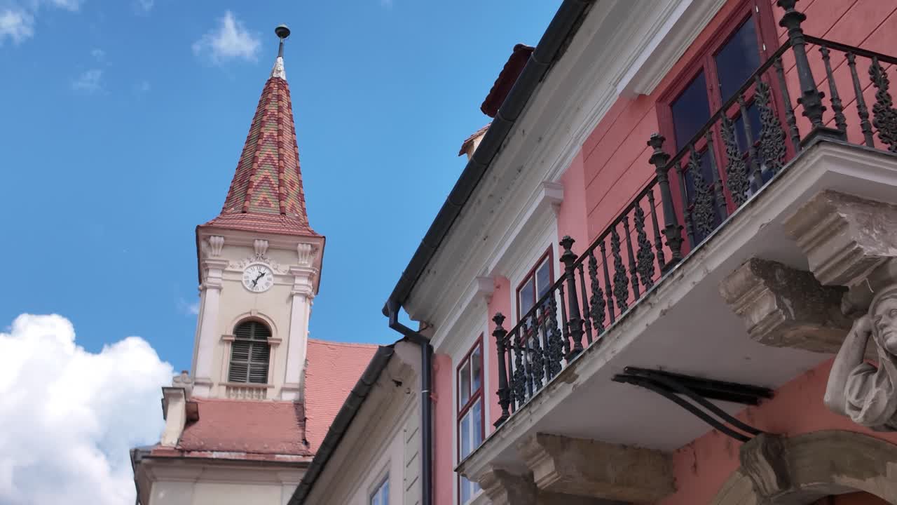 Exterior view highlighting the architectural details of a house with sculpted caryatides, framed by the Reformed Church behind