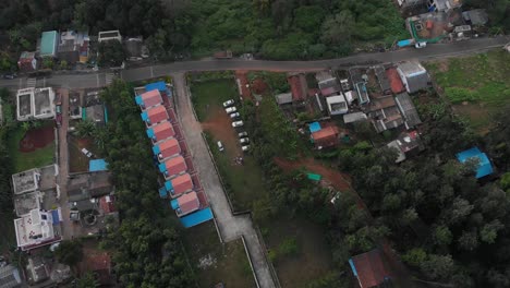 Aerial-bird's-eye-view-over-identical-colorful-twin-buildings-in-line-in-a-fresh-natural-neighborhood-with-green-trees-around,-development-concept