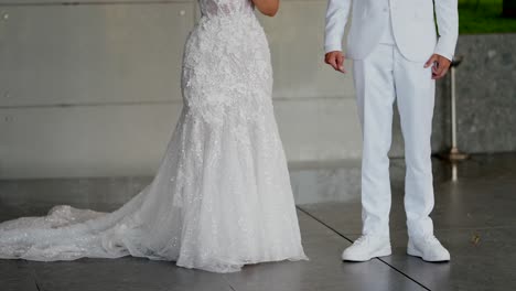 bride in lace wedding dress, groom in white suit with sneakers on modern polished floor