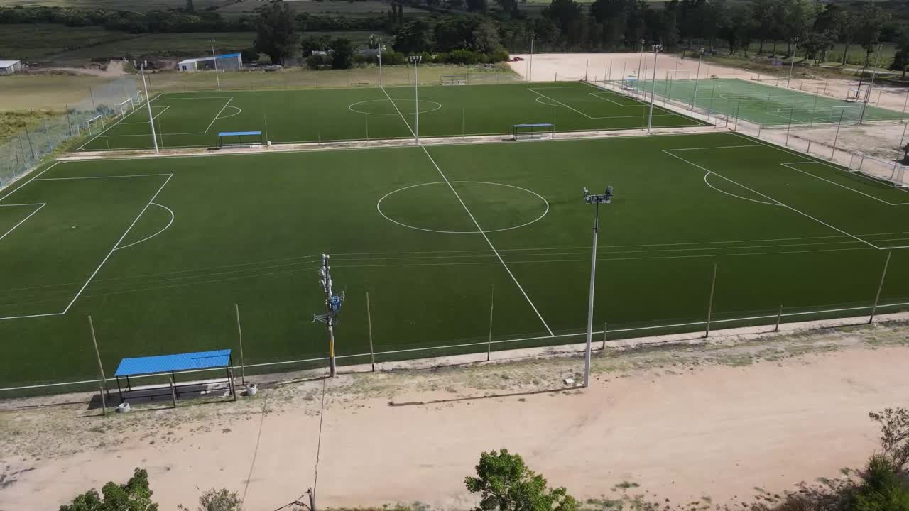 High-angle view of several vibrant green soccer fields, showcasing well-maintained artificial turf and surrounding infrastructure