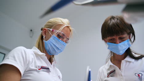 medics wearing masks work in the dental clinics. focused dentist and nurse from low angle view.