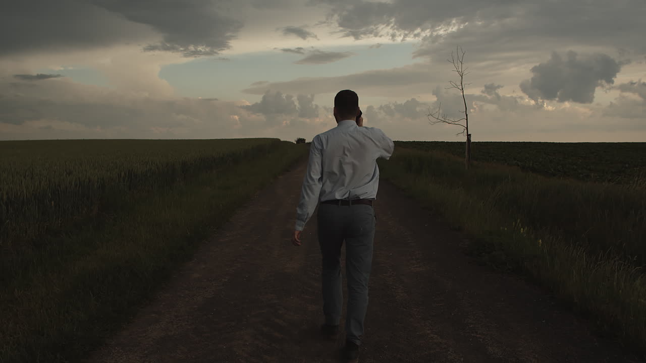 매니저는 들판 한가운데 밖에서 휴대폰으로 누군가에게 전화를 걸고 걸어 나갑니다.