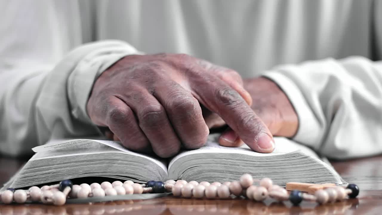 manos rezando sobre una biblia con vídeos de stock de personas