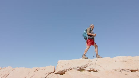 Happy-senior-biracial-man-in-mountains-hiking,-in-slow-motion