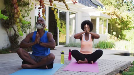 Afroamerikanisches-älteres-Paar,-Das-Yoga-Praktiziert-Und-Im-Sonnigen-Garten-Meditiert