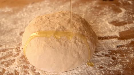 olive oil being poured over dough on a floury table