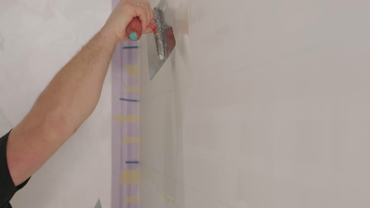 Man plastering the walls with finishing putty in room with putty spatula