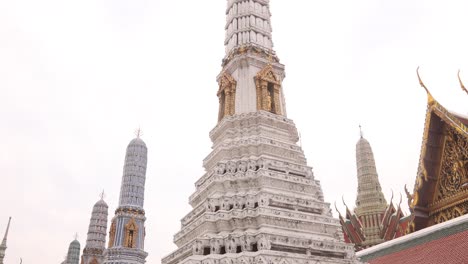 looking-up-at-towering-detailed-pagoda-spires-in-a-buddhist-temple-complex-in-the-Rattanakosin-old-town-of-Bangkok,-Thailand