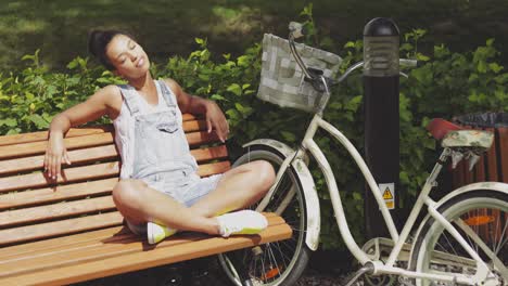 Woman-enjoying-sun-on-bench-in-park