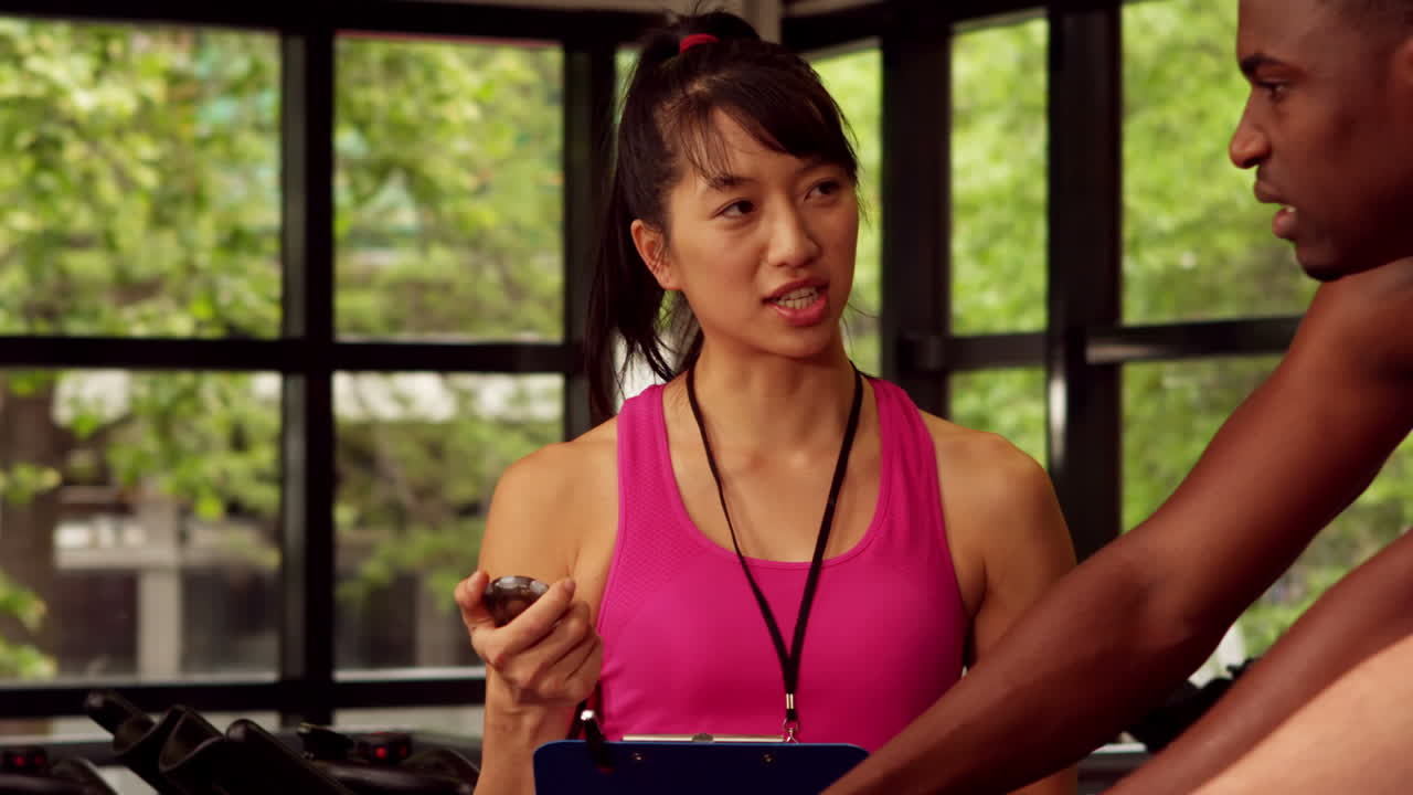 Happy female trainer assisting men while biking