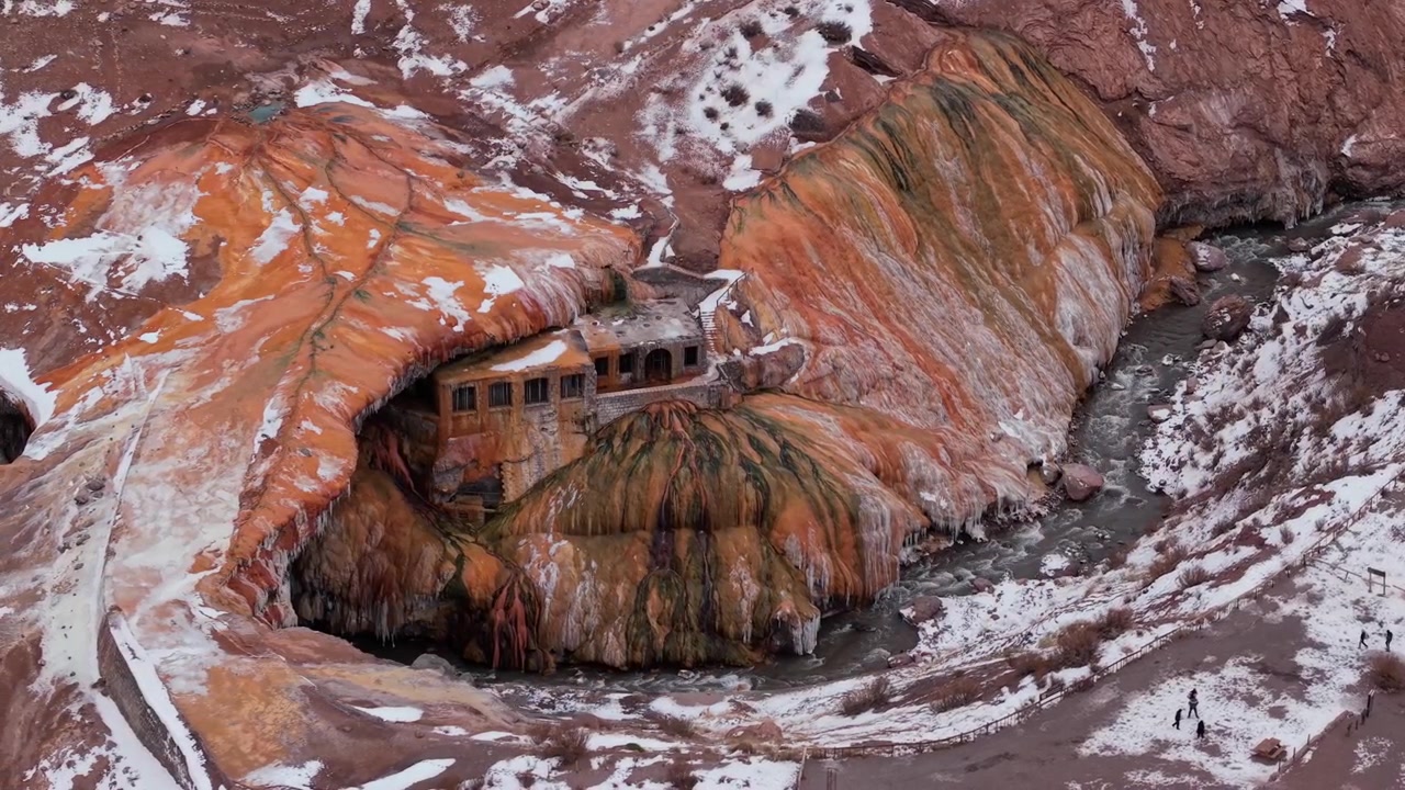 Formazioni minerali colorate circondano le rovine del monumento Puente del Inca nella Mendoza innevata, panoramica aerea con drone.